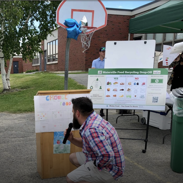 Man kneeling in front of podium, looking at winning Waterville drawing